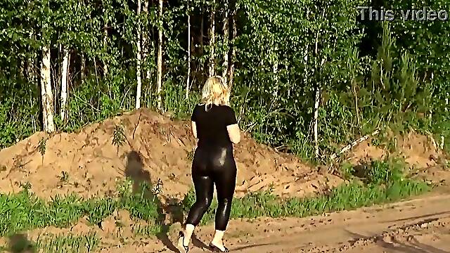 Undressed large booty in leather leggings on a walk in the park
